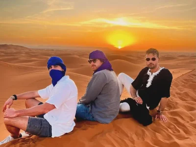 a group of men sitting on sand in the desert