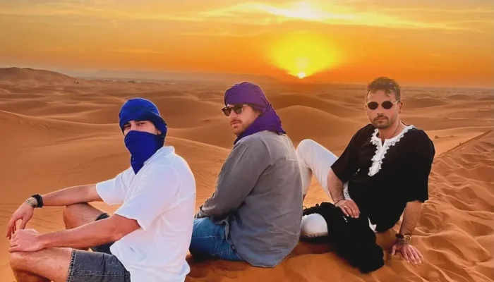 a group of men sitting on sand in the desert