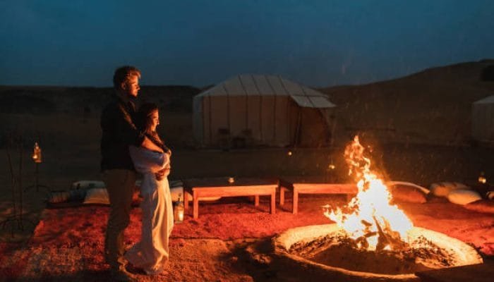 a man and woman standing next to a fire
